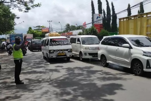 Seorang anggota polisi mengatur arus lalu lintas yang macet akibat antrean kendaraan yang akan mengisi BBM bersubsidi jenis solar di salah satu SPBU di Kabupaten Lombok Barat, NTB,